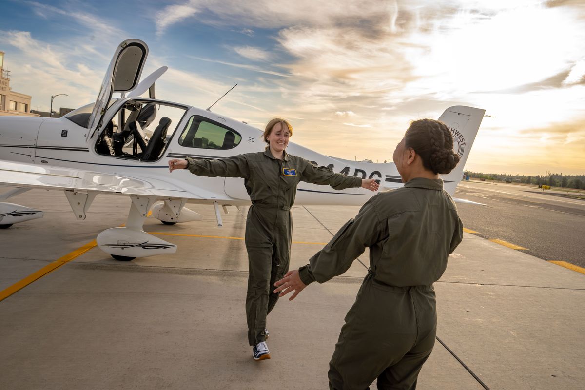 After flying with their flight instructors in different planes, AFJROTC cadets Katie Dewitt, 16, and Evelyn Nesselrode, 18, rush to embrace each other on Friday after landing back at Felts Field.  (COLIN MULVANY/The Spokesman-Review)