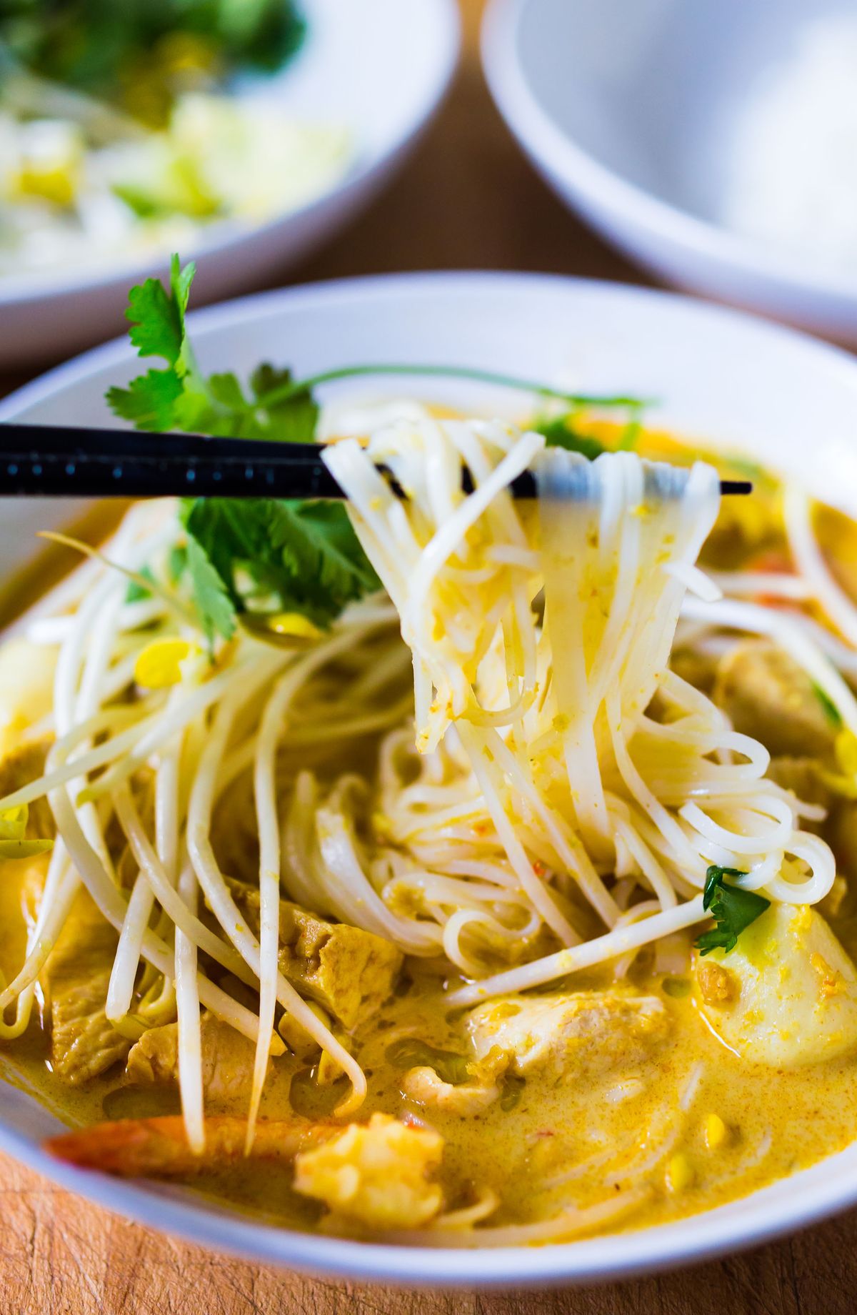 Top bowls of Curry Laksa with fresh bean sprouts, fresh cilantro and mint. (Sylvia Fountaine)