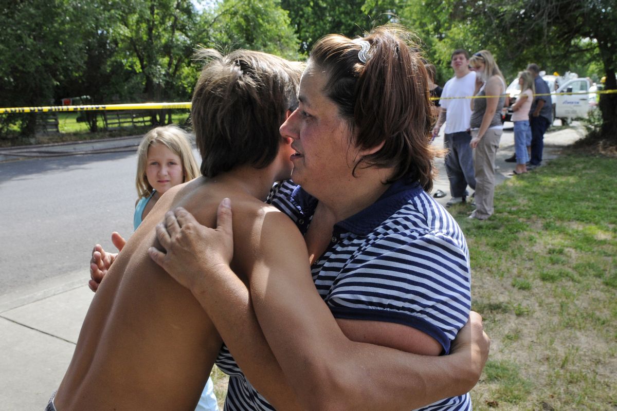 Kim Staggs, right, is comforted by neighborhood children after her aunt was killed in a house fire, July 15, 2011, on the 4200 block of east Princeton in Spokane, Wash. (Dan Pelle / The Spokesman-Review)