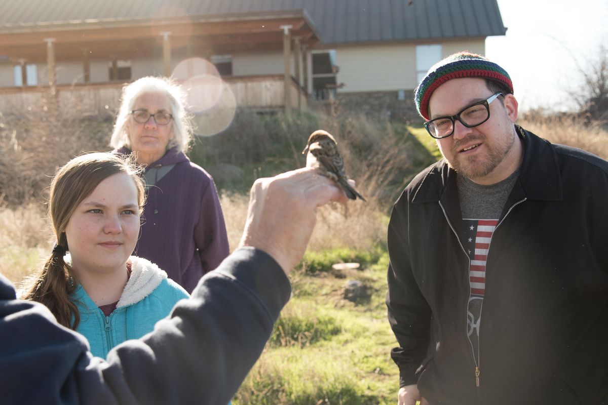 Chris Baugh, right, Haven Baugh and Frances Peterson watch a member of the Lower Columbia Basin Audubon Society hold up a common house sparrow caught on Saturday, Feb. 10, 2018. (Eli Francovich / The Spokesman-Review)