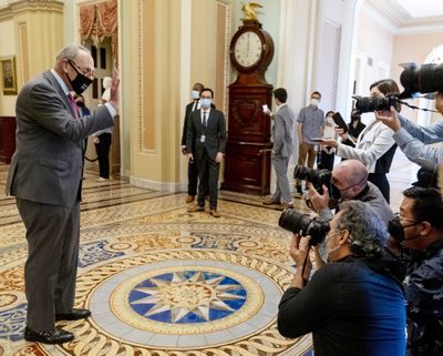 Senate Majority Leader Chuck Schumer of New York walks off the Senate floor and speaks to members of the media Tuesday after the Senate approved a bipartisan $1 trillion infrastructure bill in Washington.  (Andrew Harnik/Associated Press)