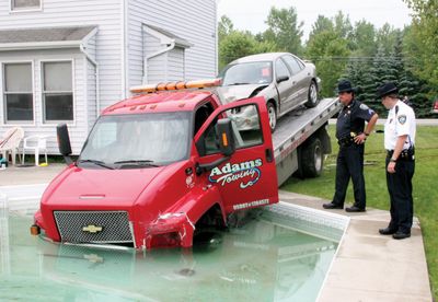 Sgt. Kevin Locicero, left, and Capt. Bruce Elliot, of the Niagara County Sheriff’s Department, examine a truck that drove into a pool in Lockport, N.Y., on Thursday. Police said the driver was juggling two cell phones. (Associated Press / The Spokesman-Review)
