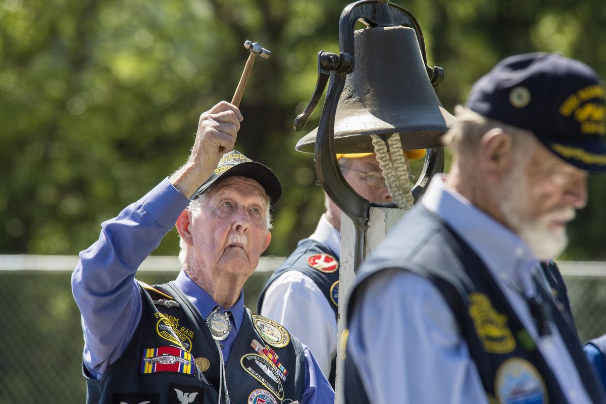 Tom DePew, WWII U. S. Navy submariner, rings the bell as the names of ships lost to war are read aloud during the Laying of the Wreath Ceremony, May 29, 2017, on Honeysuckle Beach in Hayden Lake, Idaho. (Dan Pelle / The Spokesman-Review)