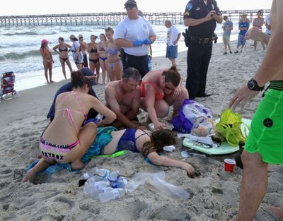 Emergency responders assist a teenage girl at the scene of a shark attack in Oak Island, N.C., on Sunday.