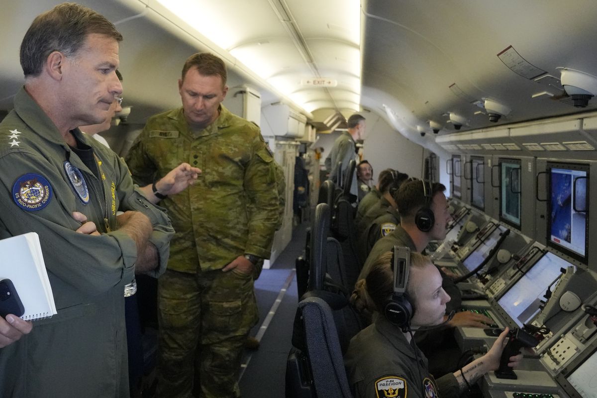 Admiral John C. Aquilino, left, Commander of the U.S. Indo-Pacific Command (INDOPACOM), looks at videos of Chinese structures and buildings on board a US P-8A Poseidon reconaisance plane flying at the Spratlys group of islands in the South China Sea on Sunday March 20, 2022. A U.S. Navy plane carrying a top American military commander was threatened repeatedly by radio on Sunday to leave the airspace over Chinese-occupied island garrisons in the disputed South China Sea, but the aircraft pressed on defiantly with its reconnaissance in brief but tense standoffs witnessed by two Associated Press journalists invited onboard.  (Aaron Favila)