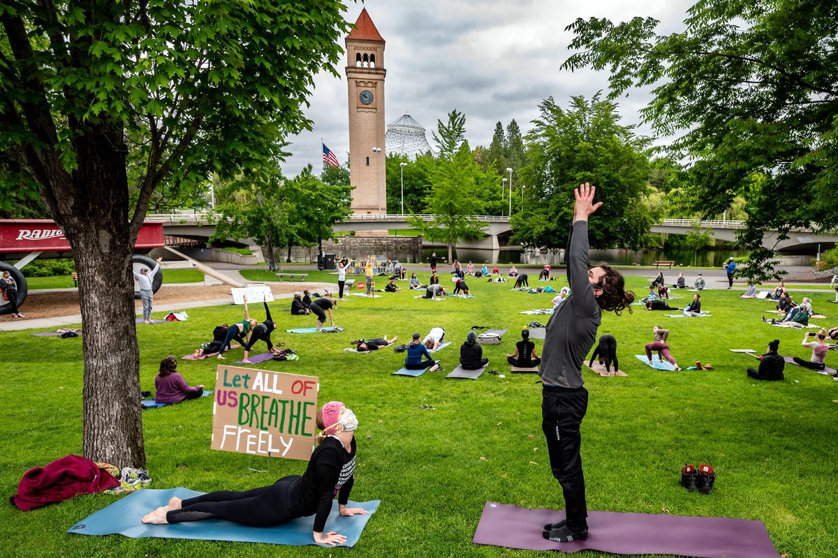 Meagan Robison, left, and Jonas Hawk join about 100 other people taking part in a moving meditation peaceful demonstration held in silence at the Red Wagon in Riverfront Park, Sunday morning, June 7, 2020. (Colin Mulvany / The Spokesman-Review)