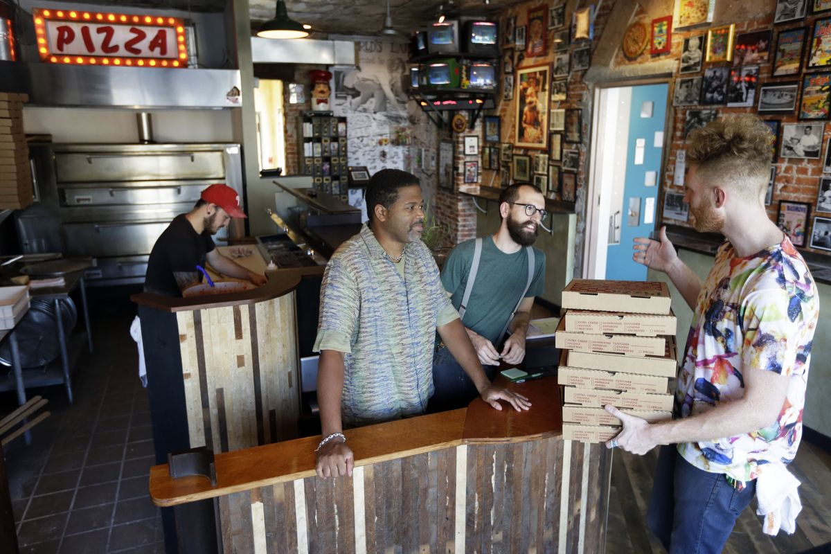 In this Wednesday, Sept. 12, 2012 photo, the owners of Pizza Brain, from left, Joseph Hunter, Michael Carter, Ryan Anderson, and Brian Dwyer work the storefront in Philadelphia.  Hundreds of people turned out for the grand opening of Pizza Brain this month in Philadelphia
