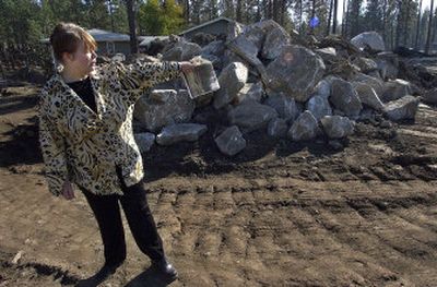 
Connie Sirchuk points toward the well that has dried up since the summer road construction along Nine Mile Road in Nine Mile Falls.  The Washington Department of Transportation says it is not responsible for removing the pile of boulders that was also left after the road construction was completed. 
 (Photos by Liz Kishimoto / The Spokesman-Review)