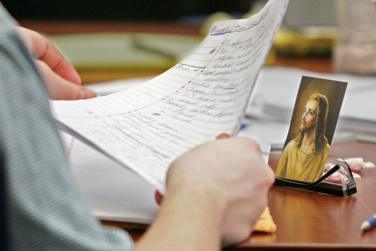 Brogan Rafferty, 17, sorts papers at the defense table next to a photo of Jesus Christ propped up on a pair of eyeglasses during his murder trial in the Summit County Common Pleas courtroom in Akron, Ohio on Friday, Oct. 12, 2012. Rafferty and an adult accomplice are charged with three killings in a plot to lure victims through phony Craigslist job offers. (Phil Masturzo / Akron Beacon Journal)