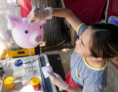 Rosa Chong with Character Cotton Candy, creates a pig face on an order of cotton candy Friday in at Pig Out in the Park in Riverfront Park.  (Colin Mulvany/THE SPOKESMAN-REVIEW)