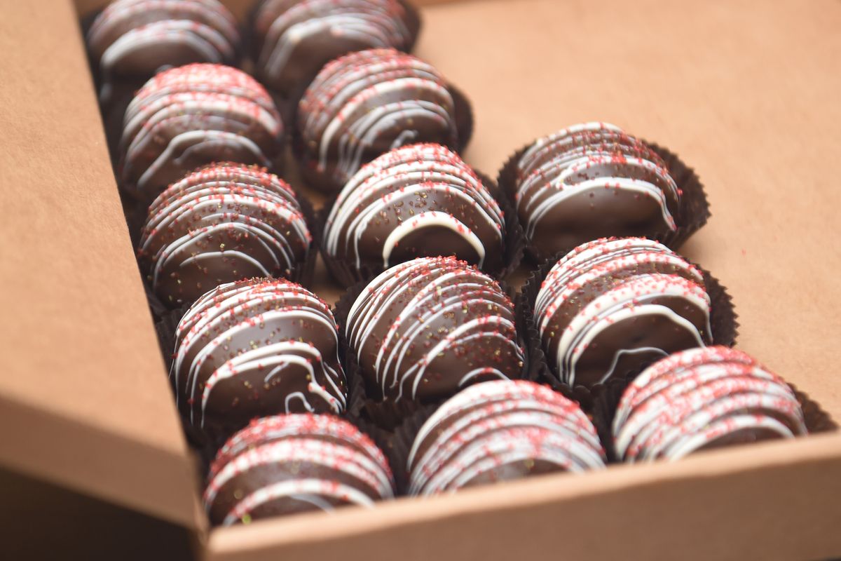 Truffles of red velvet cake covered with chocolate and decorated are packed for resale at Spokandy on Feb. 12, 2020, in downtown Spokane. Truffles, made for wholesale, are a side business of Spokandy, the longstanding boutique chocolate shop. (Jesse Tinsley/The Spokesman-Review)