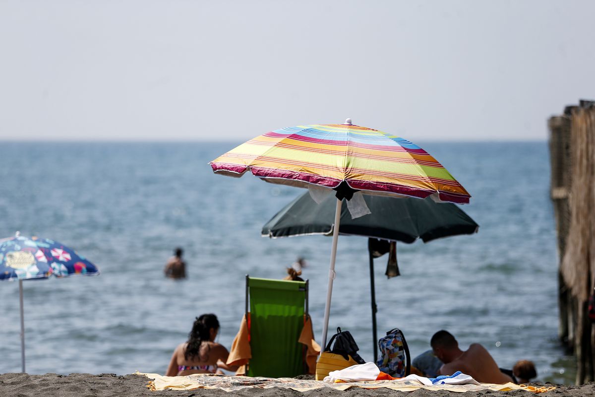 People enjoy a day at the beach, in Ostia, in the outskirts of Rome, Saturday, Aug. 14, 2021. A heat wave settled over southern Europe threatened temperatures topping 113 degrees in many parts of the Iberian Peninsula on Saturday while Italian authorities expanded to 16 the number of cities on red alert for conditions that can pose a health risk to the elderly and vulnerable.  (Cecilia Fabiano/ LaPresse)