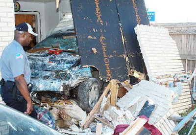 
A police officer examines the scene of an accident where a vehicle went airborne after running off a major highway and plowed through a house, landing on top of a man sleeping in his bed in Pine Bluff, Ark., on Sunday. 
 (Associated Press / The Spokesman-Review)