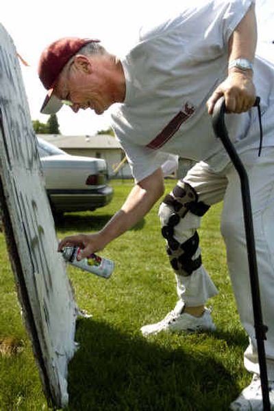 
Larry Schreck leans on his cane to paint a sign at his fruit stand in Millwood Thursday afternoon. Schreck was hit by a car and seriously hurt in March. 
 (Holly Pickett / The Spokesman-Review)