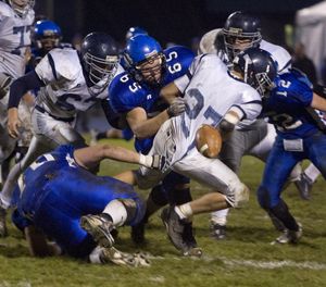 Lake City's Allen Carmichael fumbles the ball as Coeur d'Alene's Andrew Burgin (65) and Joe Roletto (12) tackle him Friday night at Lake City High School. Coeur d'Alene was able to capitalize on teh fumbel to push thier next drive for a touchdown in the second quarter. BRUCE TWITCHELL/ Special to The Spokesman-Review