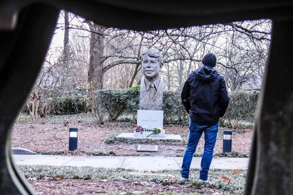 A person stands in front of a bust of former President Jimmy Carter where people laid flowers in his memory at the Carter Presidential Center in Atlanta, on Dec. 29, 2024. Jimmy Carter, the 100-year-old former U.S. president and Nobel peace laureate who rose from humble beginnings in rural Georgia to lead the nation from 1977 to 1981, has died, his nonprofit foundation said December 29.   (Alex Wroblewski/AFP/GETTY IMAGES NORTH AMERICA/TNS)