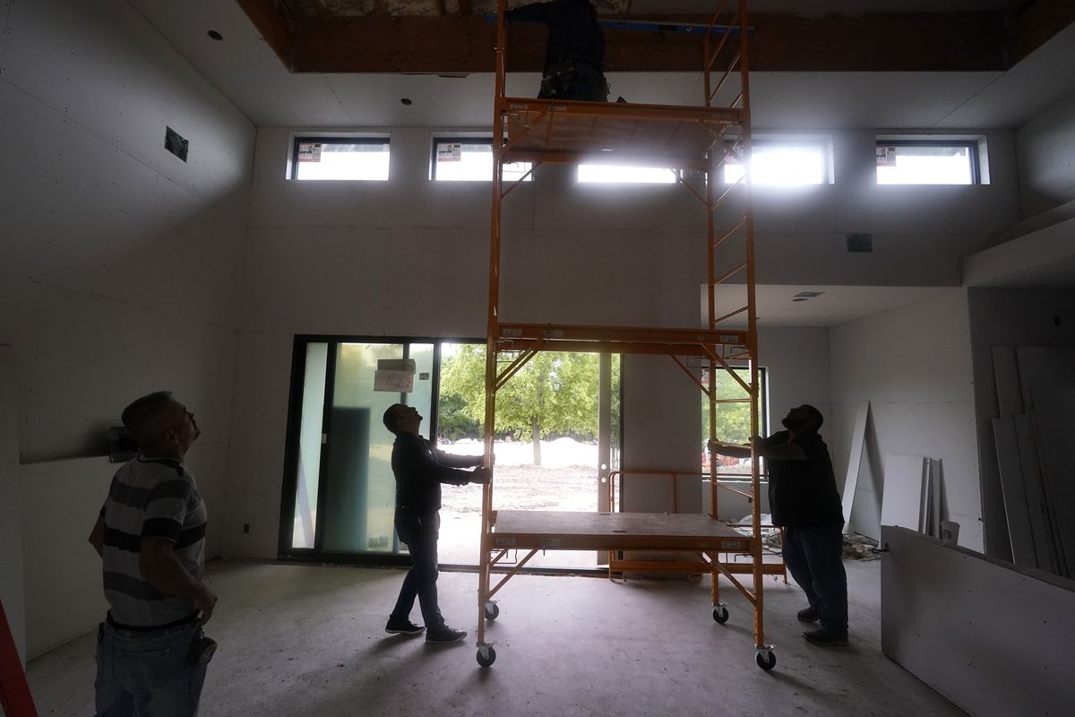 Workers move a scaffolding into place to apply sheetrock to the ceiling at a home under construction in Plano, Texas, Tuesday, May 3, 2022. There are an estimated 2 million fewer immigrants than expected in the United States, helping fuel a desperate scramble for workers in many sectors, from meatpacking to homebuilding, that are also contributing to shortages and price increases.  (LM Otero)