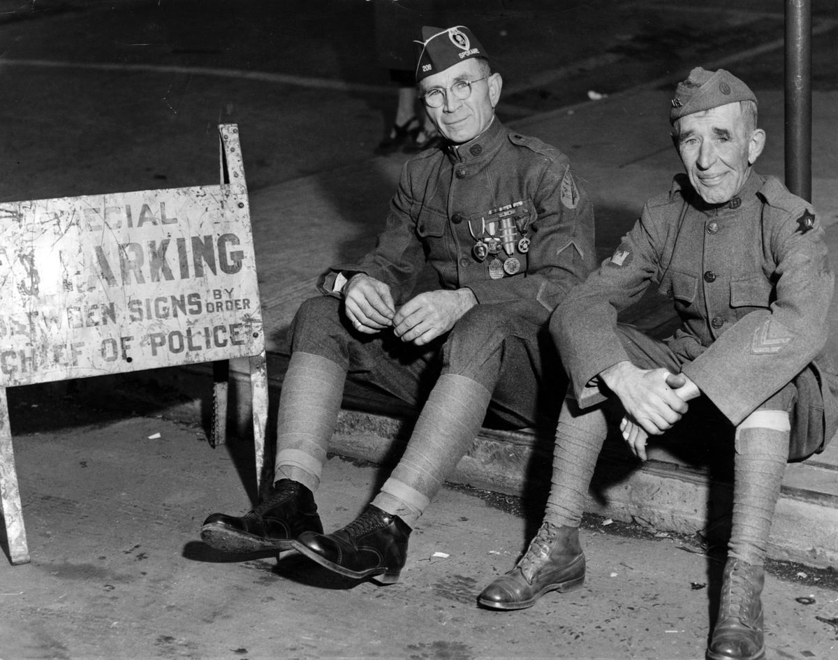 Participating in Spokane’s observance of Armistice Day on Nov. 11, 1950 were these veterans of World War I, pictured as they rested on a curb at the end of a parade. Pat Paseato, left, served with the 91st division and Charles V. Flowers served with the 6th division.  (Spokesman-Review archives)