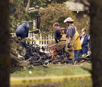 Firefighters sift through charred remains after a small plane crashed into a rental house in Gearhart, Ore., on Monday.  (Associated Press / The Spokesman-Review)