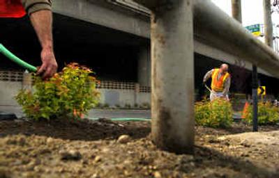 
Scott Flowers, right, an employee of the Davenport Hotel engineering department, works on landscaping around the Lincoln Street exit ramp off Interstate 90 on Thursday morning in Spokane. The beautification project funded by Walt Worthy and coordinated by the Downtown Spokane Partnership, the city of Spokane and the state Department of Transportation is scheduled to be completed by Monday. 
 (Jed Conklin / The Spokesman-Review)