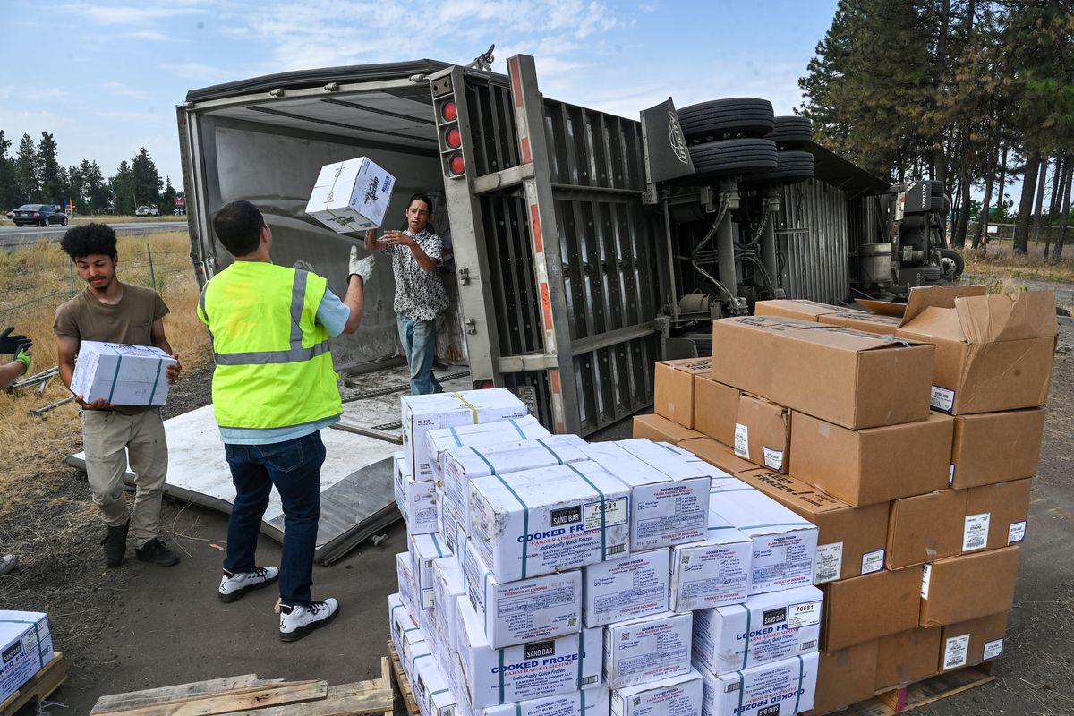 Boxes of cooked frozen farm-raised shrimp, Angus beef patties and hot Italian Beyond Sausage plant-based links are unloaded from a crashed semitruck Monday near Geiger Boulevard and Spotted Road. The truck was involved in a crash with a vehicle suspected to have been driven by a drunken driver.  (Dan Pelle/The Spokesman-Review)
