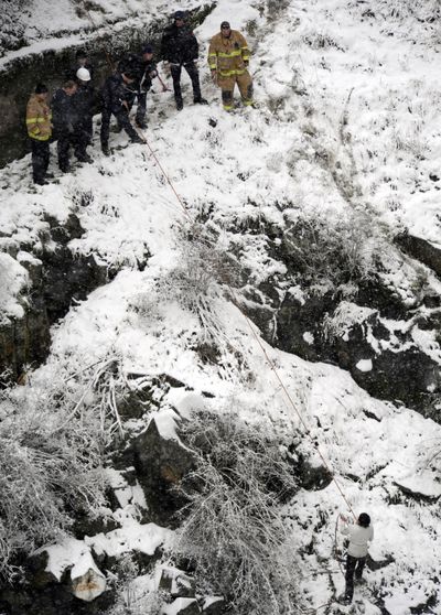 A man, seen in the lower right, prepares to climb to safety after Spokane Fire Department rescuers threw a rope down to him after he was seen in the Spokane River under the Monroe St. bridge on Wednesday, Dec. 29, 2010. (Jesse Tinsley / The Spokesman-Review)