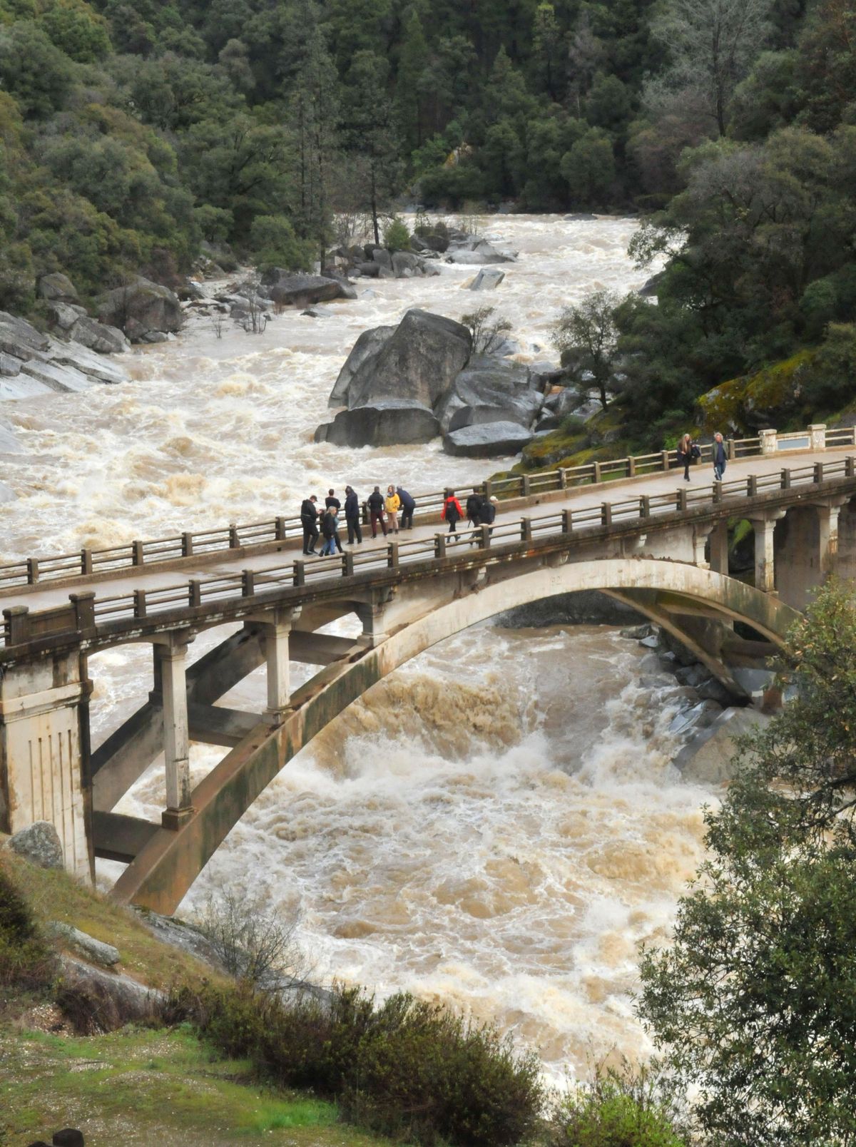 Spectators gather on the historic Highway 49 bridge over the South Fork Yuba River Thursday, March 22, 2018 to witness an intense amount of rain and snowmelt runoff rush downstream during Thursday’s atmospheric river event. (Elias Funez / Associated Press)
