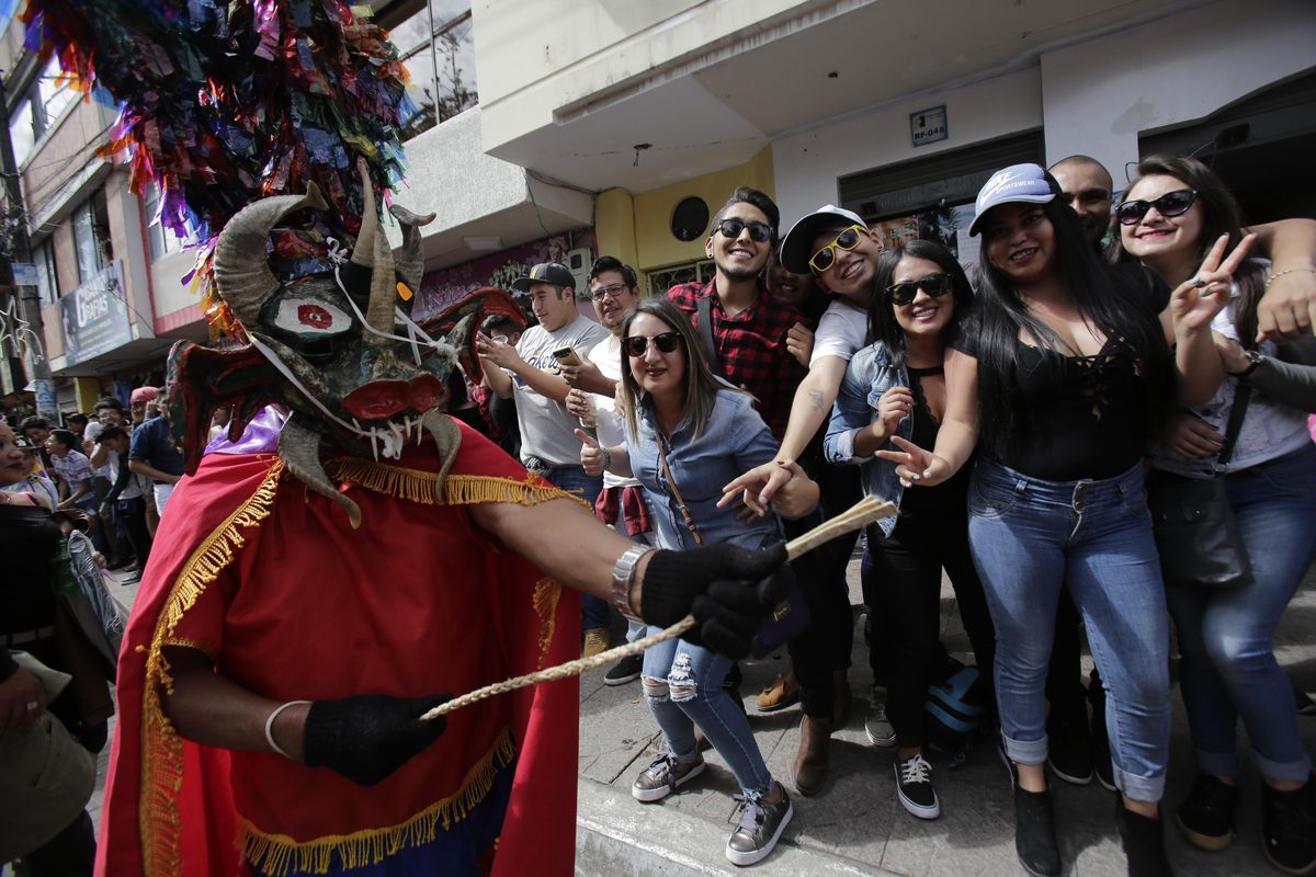 Revelers watch as people dressed as devils parade past during the traditional New Year