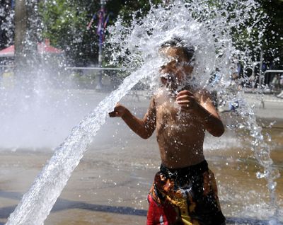 Downtown cooldown: Carlos Rodriguez, 5, of Seattle, gets a faceful of spray from the Rotary Fountain in Riverfront Park to cool off as temperatures reached into the 90s July 3 in Spokane. (Dan Pelle / The Spokesman-Review)
