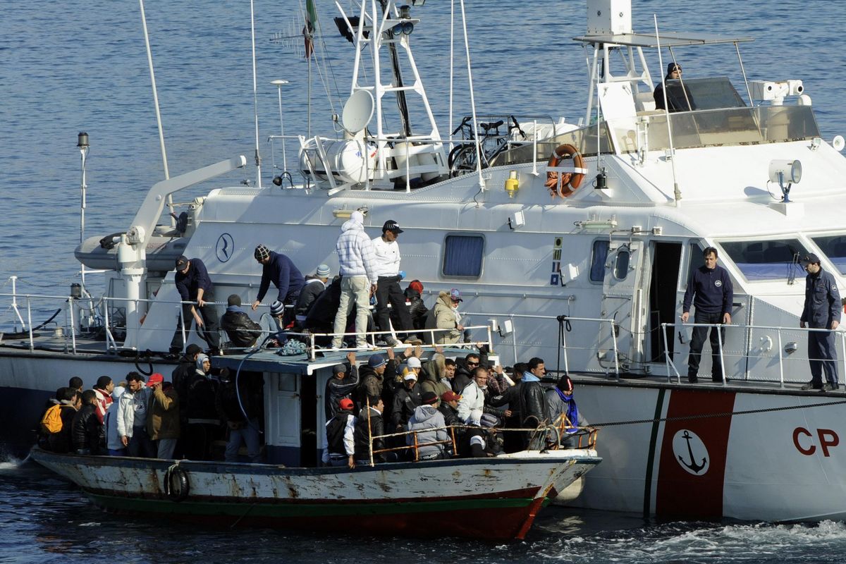 In this Sunday, Feb. 13, 2011 file photo an Italian Coast Guard vessel rescues a boatload of would-be migrants believed to be from North Africa in the waters off the Sicilian island of Lampedusa, Italy. (Daniele La Monaca / ASSOCIATED PRESS)