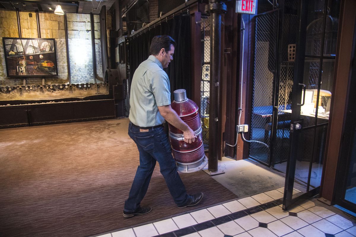 Spencer Sowl, manager of Steam Plant Square operations, carries the red beacon from atop of the stacks to a safe location near the base of the stacks, July 13, 2017. The beacon was recently removed after being replaced by LED lights. (Dan Pelle / The Spokesman-Review)