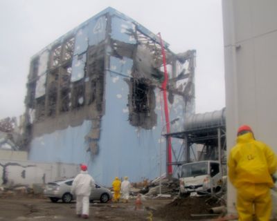 Workers in protective suits conduct a cooling operation by spraying water at the damaged No. 4 unit of the Fukushima Dai-ichi nuclear complex in Okumamachi, northeastern Japan, on Tuesday. (Associated Press)