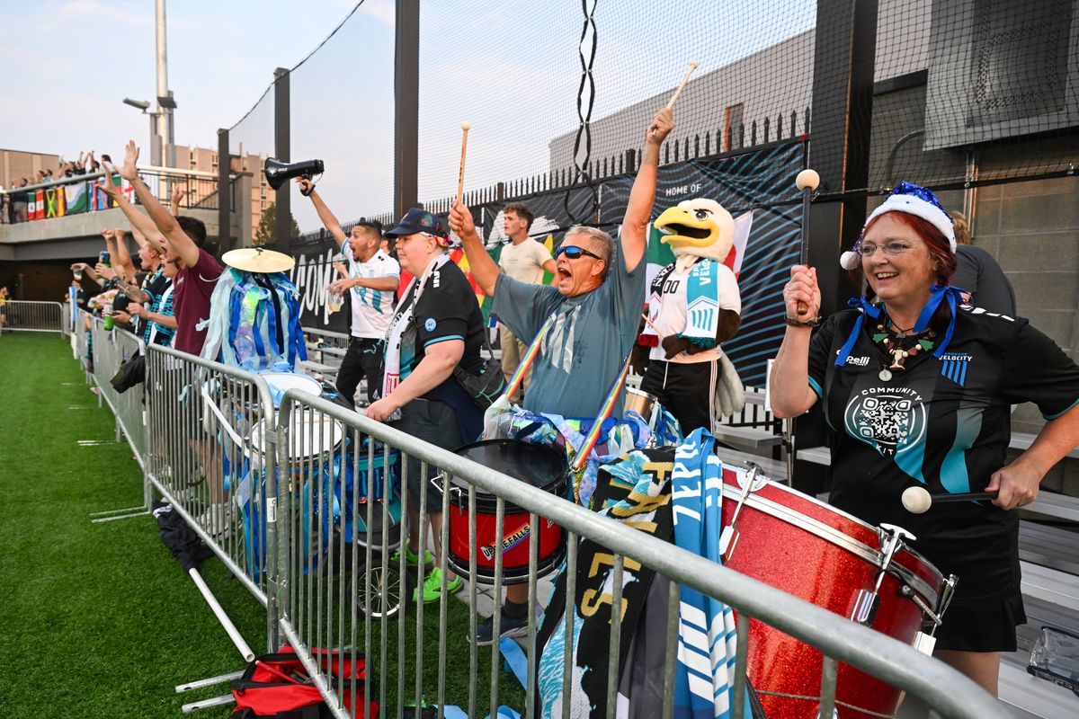 From right, drummers Lena Cooley, Tim Pearson and Elizabeth Wawrzyniak, along with group leader Andres Kehoe, waving a bullhorn, erupt with cheers as the Spokane Velocity soccer team scores a goal at the other end of the pitch inside One Spokane Stadium Saturday, July 27, 2024. The bleachers at the south end of the field are occupied by the 509 Syndicate, the fan group for the Velocity, who wave flags, lead cheers and pound drums throughout the home games.  (Jesse Tinsley/THE SPOKESMAN-REVIEW)