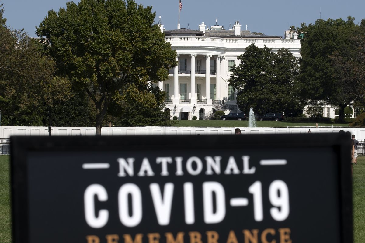 The White House is seen in the background as sign of the National COVID-19 Remembrance, event at The Ellipse outside of the White House, Sunday, Oct. 4, 2020, in Washington. More Americans blame the U.S. government than foreign powers for the coronavirus crisis in United States, rejecting the Trump administration’s contention that China is most at fault for the spread of the disease. That