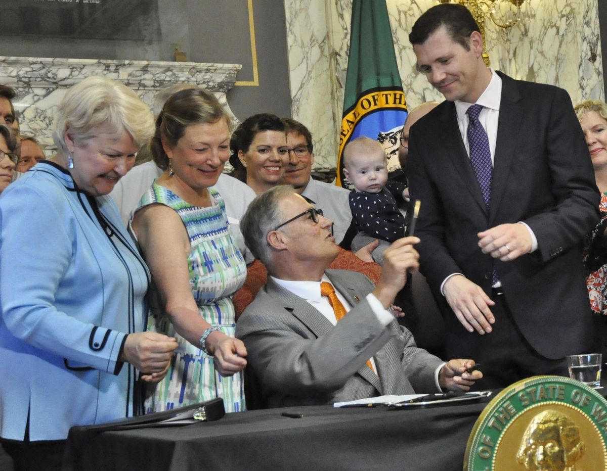 OLYMPIA – Gov. Jay Inslee hands Senate Majority Floor Leader Joe Fain, R-Auburn, the one of the pens used to sign the Paid Family and Medical Leave Act Wednesday. Fain was one of the negotiators who came up with a compromise that passed the Legislature with bipartisan support last week. (Jim Camden / The Spokesman-Review)
