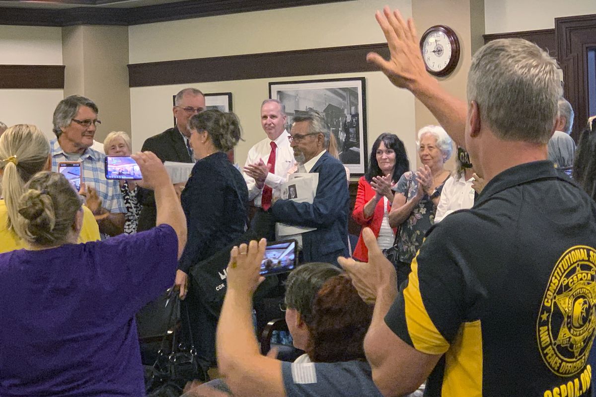Republican Rep. Priscilla Giddings, left center in black, enters her ethics committee hearing Monday, Aug. 2, 2021, to applause and shouts of encouragement from supporters in the audience in Boise, Idaho. An Idaho lawmaker accused of violating ethics rules by publicizing the name of an alleged rape victim in disparaging social media posts, and then allegedly misleading lawmakers about her actions, said in an ethics hearing Monday that she did nothing wrong and claimed the allegations against her were politically motivated.  (Rebecca Boone)