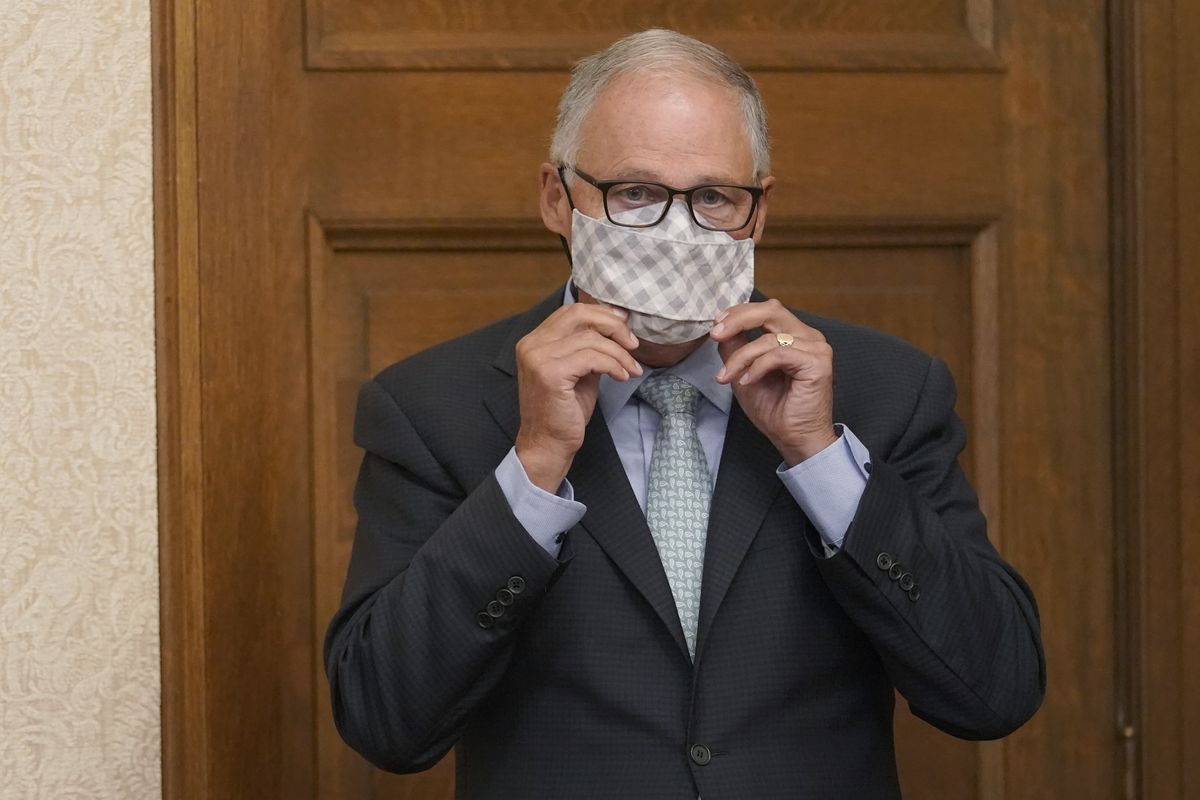 Washington Gov. Jay Inslee puts on a mask after speaking at a news conference on Aug. 18 in Olympia.  (Ted S. Warren/Associated Press)
