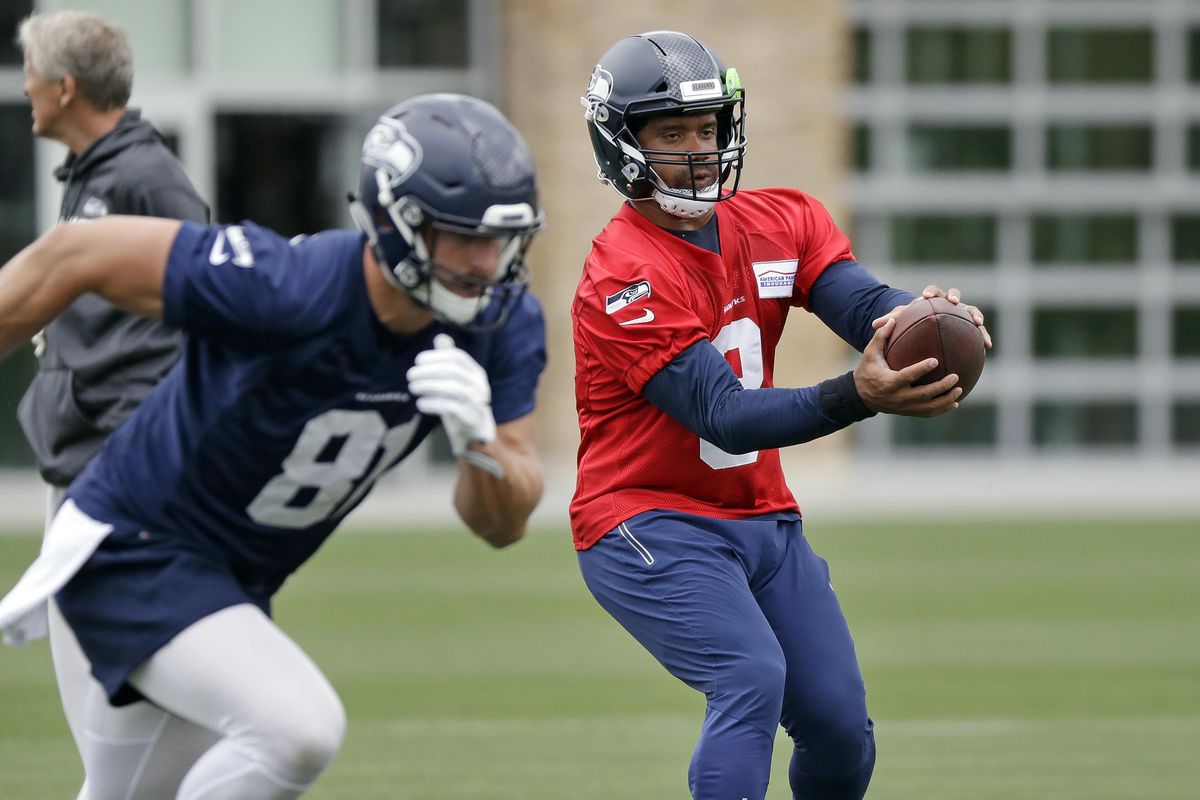 Seattle Seahawks quarterback Russell Wilson, right, reaches for the ball as tight end Nick Vannett runs the drill during an NFL football practice Thursday, June 7, 2018, in Renton, Wash. (Elaine Thompson / AP)