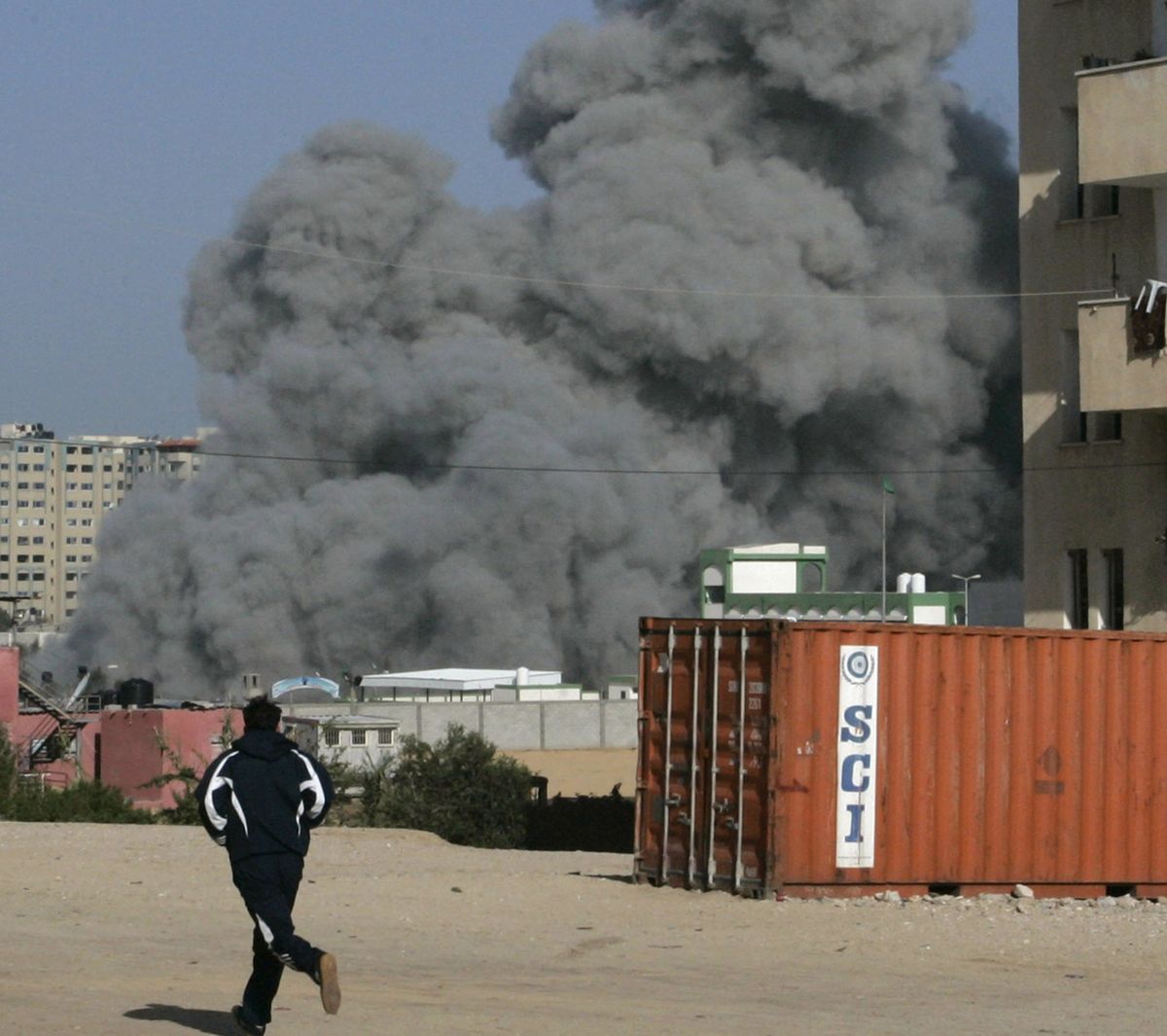 Palestinians run as an explosion is seen during an Israeli missile strike on the Hamas controlled Islamic University in Gaza City, Monday, Dec. 29, 2008. Israel