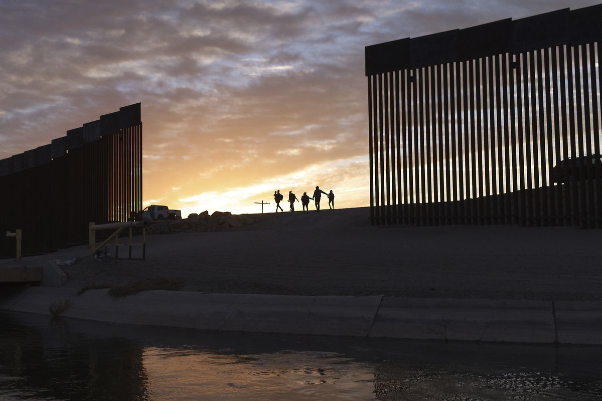 In this June 10, 2021 photo, a pair of migrant families from Brazil pass through a gap in the border wall to reach the United States after crossing from Mexico to Yuma, Ariz., to seek asylum. As the delta variant fuels an increase of COVID-19 cases in the U.S., some of President Joe Biden