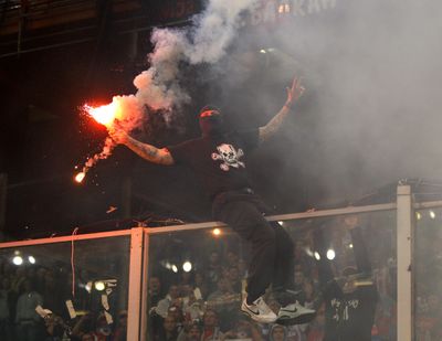 A Serbia fan climbs onto a partition to throw a flare prior to the start of a Euro 2012 qualifying soccer match against Italy.  (Associated Press)