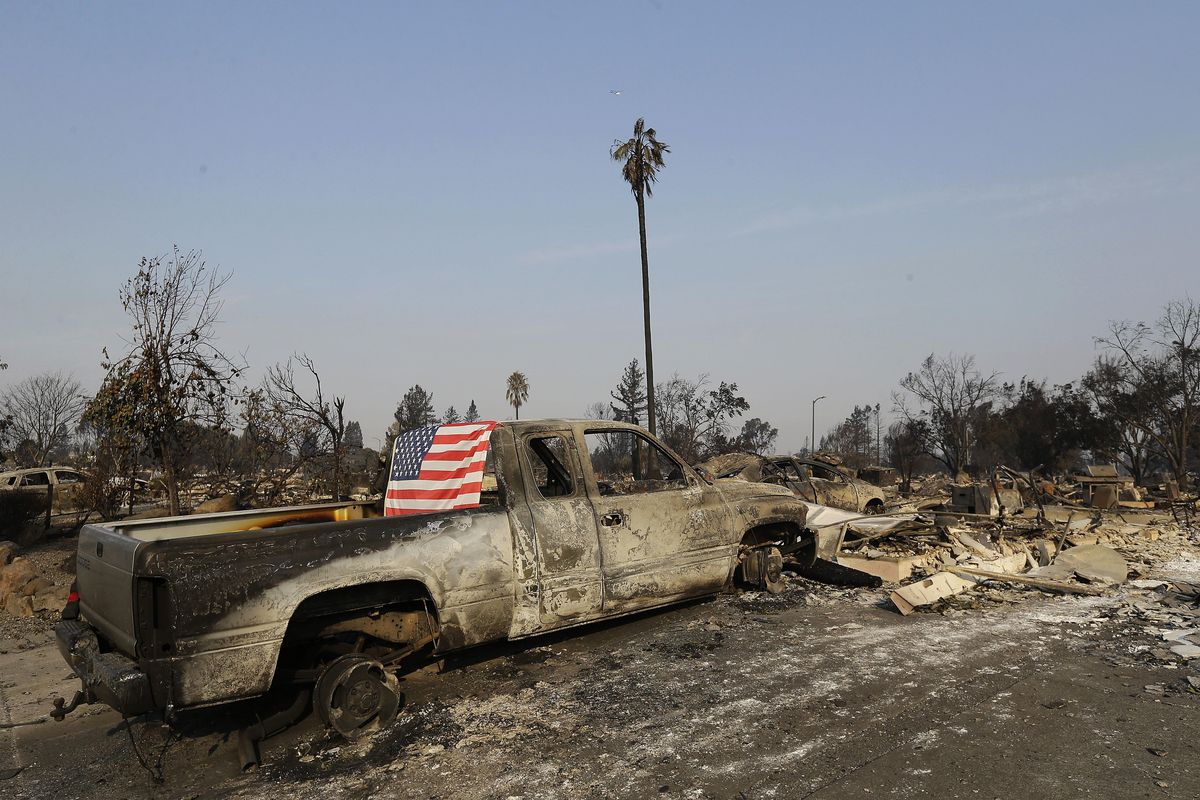 A flag is draped on the back of a truck destroyed by fires in Santa Rosa, Calif., Wednesday, Oct. 11, 2017. Wildfires tearing through California’s wine country continued to expand Wednesday, destroying hundreds more homes and structures and prompting new evacuation orders. (Jeff Chiu / Associated Press)
