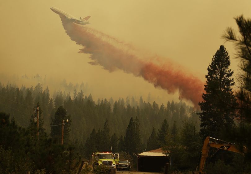 An airplane tanker flies through smoky air above a home as it drops fire retardant on a wildfire that flared up in the late afternoon near Omak, Wash., Thursday, Aug. 27, 2015. Firefighters were holding their own Thursday against the largest wildfire on record in Washington state, even as rising temperatures and increased winds stoked the flames. (Ted Warren / Associated Press)