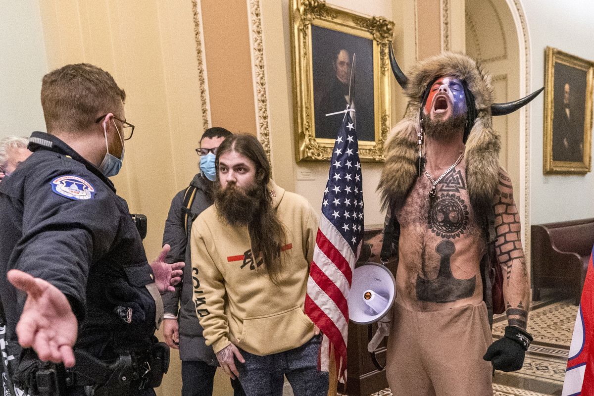 In this Wednesday, Jan. 6, 2021 photo, supporters of President Donald Trump, including Jacob Chansley, right with fur hat, are confronted by U.S. Capitol Police officers outside the Senate Chamber inside the Capitol in Washington. A judge ordered corrections authorities to provide organic food to an Arizona man who is accused of participating in the insurrection at the U.S. Capitol while sporting face paint, no shirt and a furry hat with horns.  (Manuel Balce Ceneta)