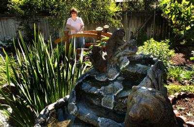 
Barbara Kusterer stands atop a hand-built bridge over one of many water features around her South Hill home. 
 (Photos by BRIAN PLONKA / The Spokesman-Review)