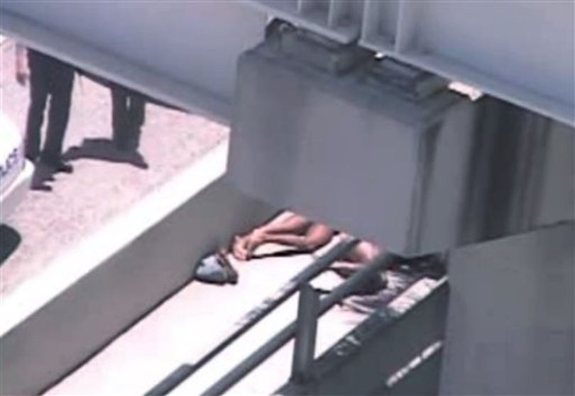 In this image taken from video, Miami police officers stand watch near a naked man, second from right, who was shot dead by a police officer when he refused to stop chewing on the face of the naked man next to him, partially obscured by a railing, on the MacArthur Causeway ramp onto Northeast 13th Street in Miami, Saturday, May 26, 2012. The victim was taken to a nearby hospital. Police say neither man's identity is known. ( (AP Photo/The Miami Herald) )