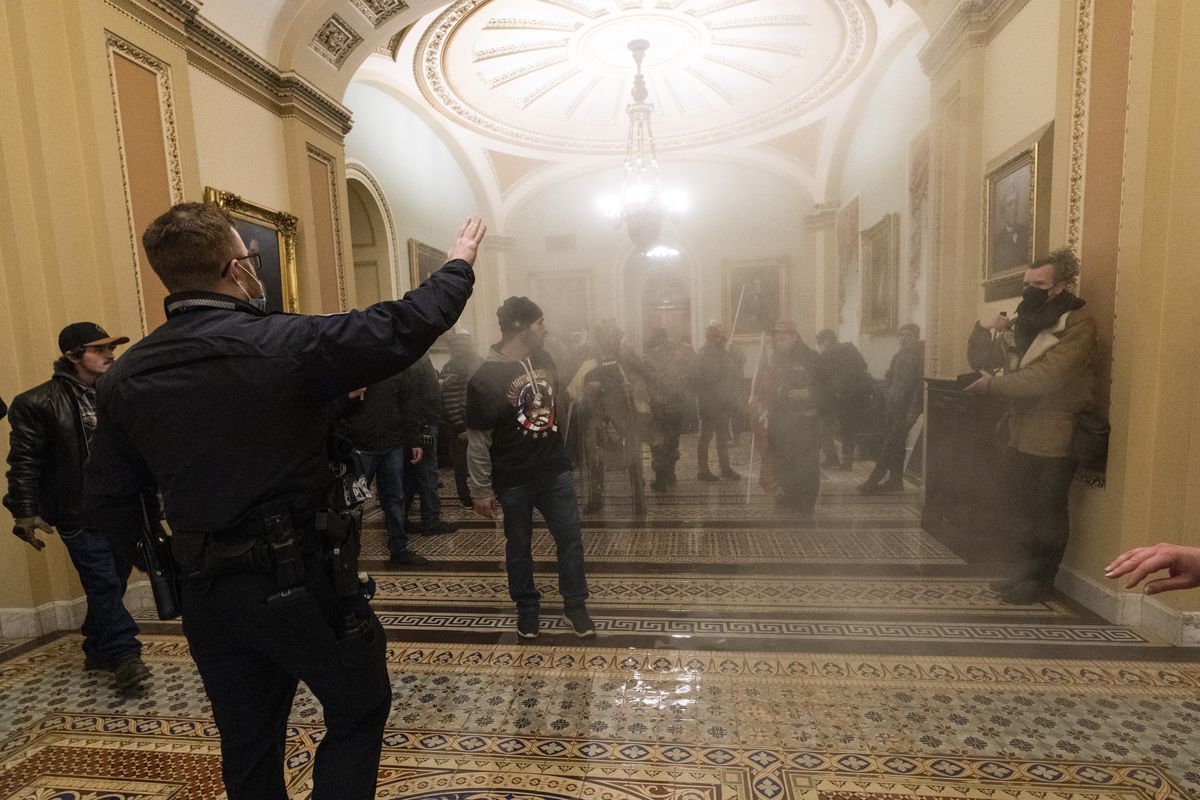 In this Jan. 6, 2021 file photo smoke fills the walkway outside the Senate Chamber as insurrectionists loyal to President Donald Trump are confronted by U.S. Capitol Police officers inside the Capitol in Washington. Arguments begin Tuesday, Feb. 9, in the impeachment trial of Donald Trump on allegations that he incited the violent mob that stormed the U.S. Capitol on Jan. 6.  (Manuel Balce Ceneta)