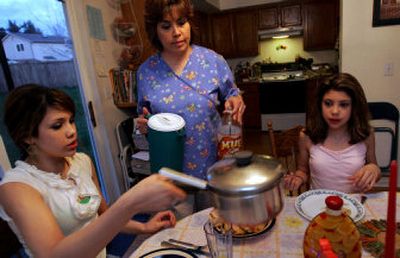 
Brittany Vigoreaux, 15, left, sits at the table for dinner with her sister Alicia, 12,  as their mother, Cindy Vigoreaux,  serves drinks recently  in Milton, Wash. 
 (Associated Press / The Spokesman-Review)