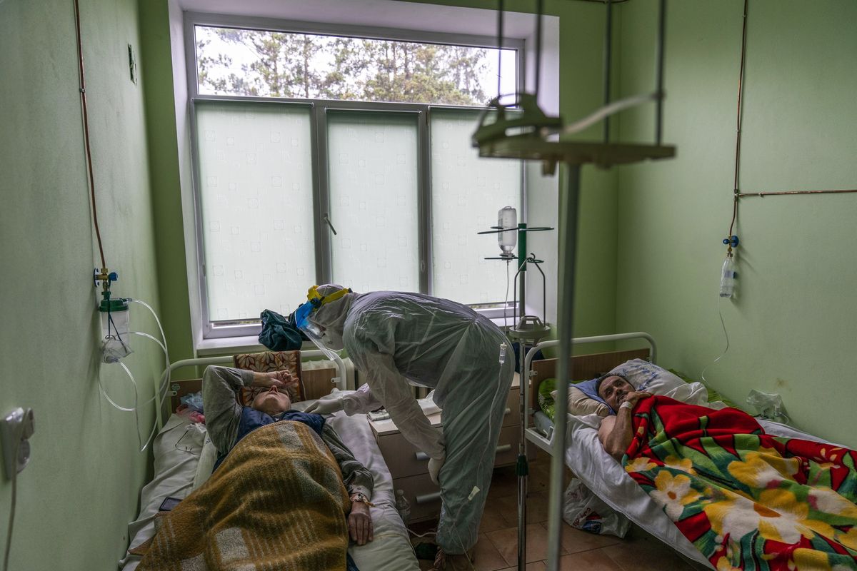 Dr. Oleh Hornostayev speaks to a coronavirus patient at a hospital intensive care unit in Stryi, Ukraine, on Tuesday, Sept. 29, 2020. Coronavirus infections in Ukraine began surging in late summer, and the ripples are hitting towns in the western part of the country. The government wants to avoid imposing a new lockdown, but officials acknowledge that the rising infections could make it necessary.  (Evgeniy Maloletka)