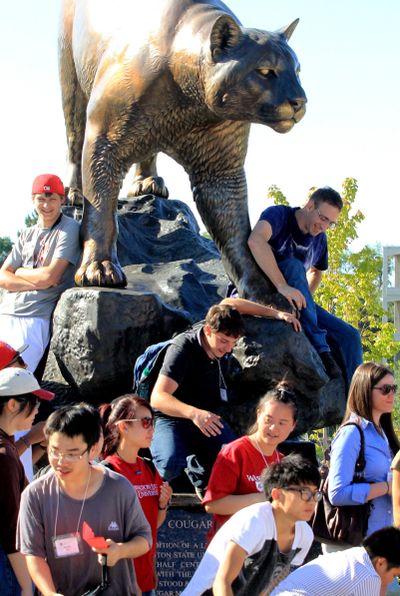Freshmen climb down from the sculpture of the Washington State University mascot, Butch, during a walking tour of the Pullman campus on Aug. 17. (Alan Berner)